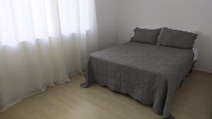 a bedroom with a bed and a window with white curtains at Casa no centro de Petrópolis in Petrópolis