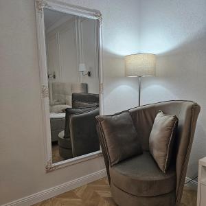 einen Spiegel in einem Zimmer mit einem Stuhl und einem Wohnzimmer in der Unterkunft Apartament M2 Vatra Dornei in Vatra Dornei