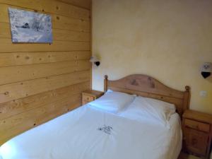 Schlafzimmer mit einem weißen Bett und Holzwänden in der Unterkunft La Ferme d'Henriette, à Samoëns in Samoëns