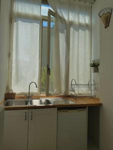 eine Küchentheke mit einem Waschbecken und einem Fenster in der Unterkunft Dolce Farinella in Putignano