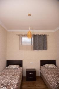 1 dormitorio con 2 camas, ventana y lámpara en Sevan Hotel en Sevan