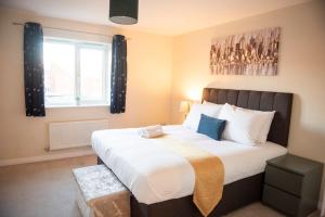 a bedroom with a large white bed with a window at Buttercup House in Saint Neots