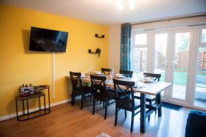 a dining room with a table and chairs and a television at Buttercup House in Saint Neots