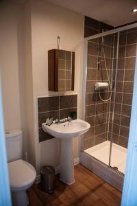a bathroom with a sink and a toilet and a shower at Buttercup House in Saint Neots