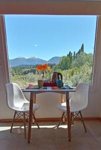 - une table avec 2 chaises et une théière dans l'établissement La Casa de los Cuadros, à Lago Puelo