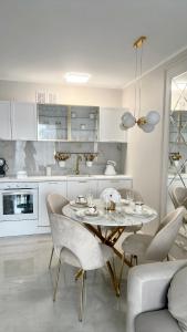 - une cuisine blanche avec une table et des chaises dans l'établissement LuxApart Apartamenty Jantar, à Jantar