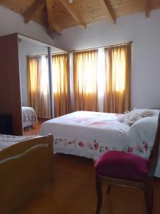 1 dormitorio con 2 camas, cortinas y silla en Muy Patagónica, Casa de Campo en Trelew