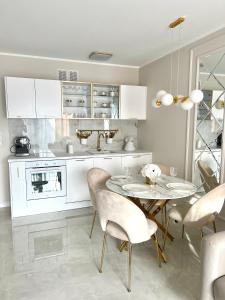 cocina blanca con mesa y sillas en LuxApart Apartamenty Jantar en Jantar