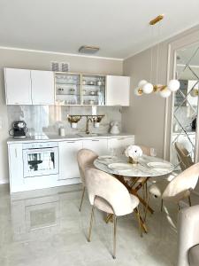 a white kitchen with a table and chairs at LuxApart Apartamenty Jantar in Jantar