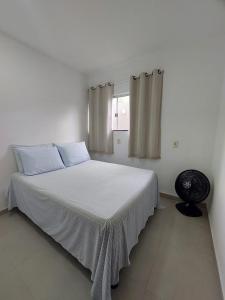 een witte slaapkamer met een bed met witte lakens en een raam bij Casa individual com piscina e area gurmet in Santa Cruz Cabrália