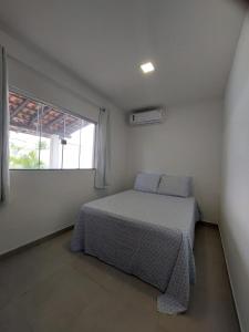 een slaapkamer met een bed in een kamer met een raam bij Casa individual com piscina e area gurmet in Santa Cruz Cabrália