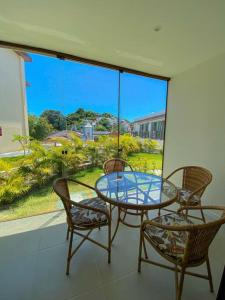 eine Terrasse mit einem Glastisch und Stühlen sowie einem Fenster in der Unterkunft Amerigo Loft Jardim - Morro de Sao Paulo Lofts in Cayru