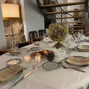 a table with a white table cloth with candles and glasses at Villa Tauria- Casa de campo em aldeia medieval in Sabugal