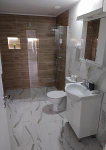 a white bathroom with a toilet and a sink at Zamak in Niš
