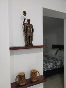 Uma estátua de um homem numa prateleira com duas canecas. em Zamak em Niš