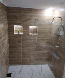 uma casa de banho com chuveiro e paredes de madeira em Zamak em Niš