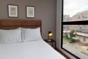 um quarto com uma cama e uma grande janela em Apartamento 2 habitaciones Unicentro Scape em Bogotá