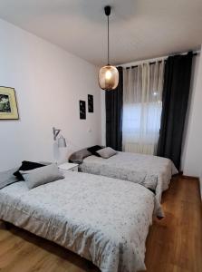 a bedroom with two beds and a pendant light at El Rincón del Pisuerga con Terraza in Cabezón de Pisuerga