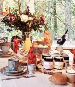 una mesa cubierta con platos y jarras de comida y flores en A Wood Lodge - zwembad - relax - natuur, en Durbuy