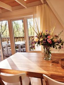 uma mesa de jantar com um vaso de flores em A Wood Lodge - zwembad - relax - natuur em Durbuy