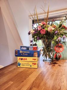 une pile de livres et un vase de fleurs sur une table dans l'établissement A Wood Lodge - zwembad - relax - natuur, à Durbuy