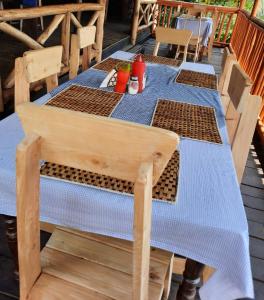 a wooden table with a blue table cloth on a deck at Dave the Cave Eco Lodge and Cultural Campsite in Rubirizi