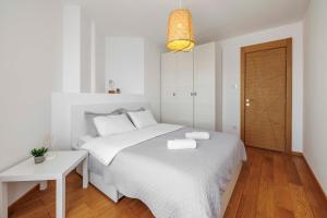 a white bedroom with a white bed and a table at Panta Rhei Luxury Apartments in Novi Sad