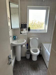 a bathroom with a toilet and a sink and a window at Home in Medway 3bedroom free sports channel, parking in Chatham