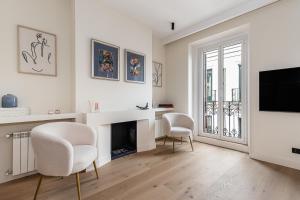 - un salon blanc avec deux chaises et une télévision dans l'établissement BNBHolder Luxury II SOL, à Madrid