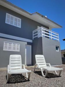 dos sillas blancas sentadas frente a una casa en Casa Bellatorres en Passo de Torres
