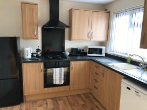 a kitchen with wooden cabinets and a black stove top oven at Lavender Cottage in Thirsk