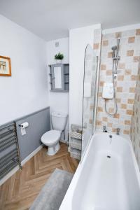 a bathroom with a white tub and a toilet at Charming Malvern Cottage with Outstanding Views in Malvern Wells