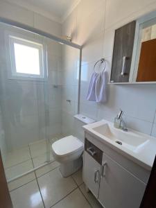a bathroom with a toilet and a shower and a sink at Casa Bellatorres in Passo de Torres