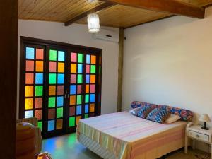 Habitación con cama y ventana colorida. en Apartamentos com cachoeira no quintal, en Ilhabela