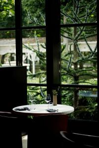 une table avec deux verres à vin devant une fenêtre dans l'établissement Maison Decoret - Relais & Châteaux, à Vichy