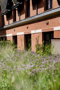 a brick building with a field of grass and purple flowers at Maison Decoret - Relais & Châteaux in Vichy