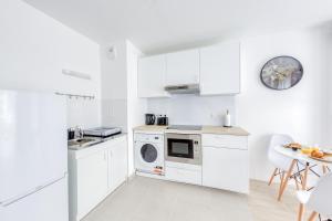a white kitchen with white cabinets and a table at Superbe T2 proche Paris métro 7 à 5 mn à pied in Ivry-sur-Seine