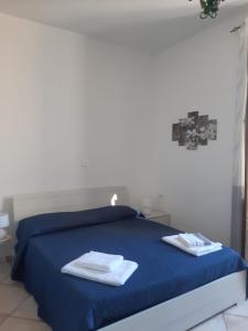 a bedroom with a blue bed with two towels on it at Appartamento Centro Storico con balcone e camino - Tarquinia in Tarquinia