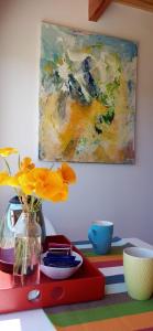 a table with a vase of flowers and a painting at La Casa de los Cuadros in Lago Puelo