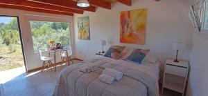 une chambre avec un grand lit avec des serviettes dessus dans l'établissement La Casa de los Cuadros, à Lago Puelo