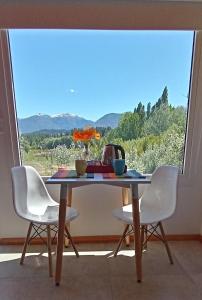 a table with two chairs and a table with a window at La Casa de los Cuadros in Lago Puelo
