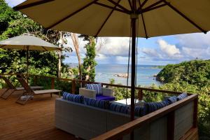 Calibishie的住宿－Blue Whale Villa - Deluxe Suite，一个带椅子和遮阳伞的阳台,并享有海景。