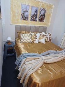 um quarto com uma cama grande com lençóis e almofadas douradas em casinha linda, 3 camas p 4 hóspedes próx do metrô em São Paulo