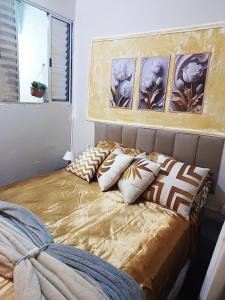 uma cama com almofadas num quarto em casinha linda, 3 camas p 4 hóspedes próx do metrô em São Paulo