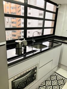 een keuken met een wastafel en een raam bij Apart Centro Acomoda 10 in Curitiba