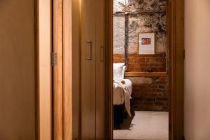 Habitación con cama y pared de ladrillo en The Thomas Gregg Apartments, en Dunedin