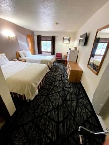 a hotel room with two beds and a mirror at Woodland Inn & Suites in Medford