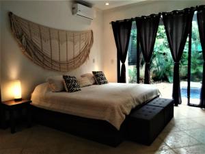 a bedroom with a large bed and a large window at Typical villa , swimming pool, 300 Meters to Langosta Tamarindo beaches in Tamarindo
