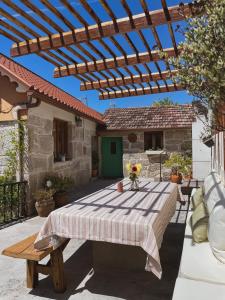 um pátio com uma mesa e uma pérgola de madeira em Casa rural familiar con vistas al rio en Galicia em Santa María