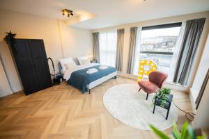 een slaapkamer met een bed en een groot raam bij Alphabet Studio Apartments including City view in Hilversum